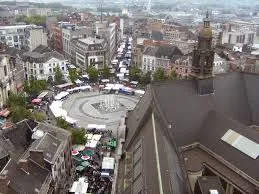 Plombier Charleroi devant le beffroi emblématique, rue animée avec bâtiments historiques en arrière-plan, ciel bleu.