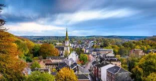 Plombier Eupen, rue pavée typique avec maisons à colombages et enseigne d'un artisan local offrant ses services.