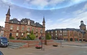 Camion de débouchage Frameries devant l'église paroissiale, rues pavées animées et architecture typique belge.