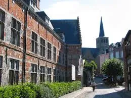 Rue animée de Lessines avec un plombier en action près d'un bâtiment historique typique de la ville, Plombier Lessines