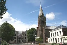 Plombier Manage vu près d'une rue pavée typique de Manage avec ses maisons en briques rouges et enseignes locales.