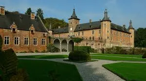 Plombier Rixensart réparant une canalisation devant l'église Saint-Sixte, avec des maisons typiques en arrière-plan.