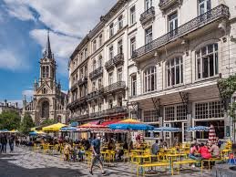 Plombier Saint Gilles camion devant maison en briques rouges typiques ville, rue animée avec piétons et commerces