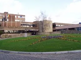 Scène urbaine à Sambreville montrant le débouchage de canalisations près de bâtiments typiques de la ville.